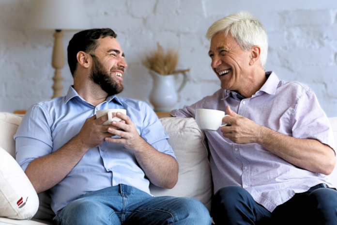 father-son-drinking-coffee-conversing-happily-on-couch