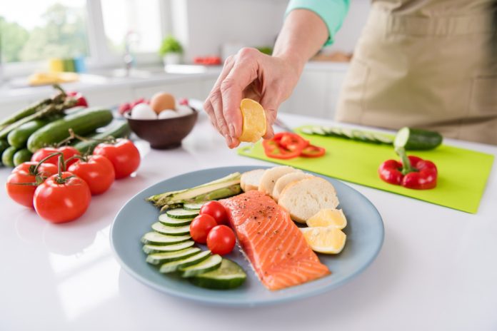 senior squeezing lemon atop salmon