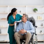 Young,Nurse,Covering,Disabled,Elderly,Man,In,Wheelchair,With,Warm