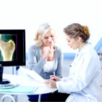 Doctor and patient reviewing x-ray, both female