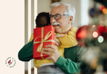 grandpa-granddaughter-hugging-sharing-gift-by-christmas-tree