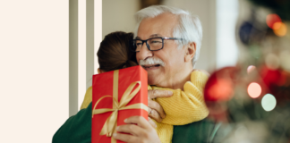 grandpa-granddaughter-hugging-sharing-gift-by-christmas-tree